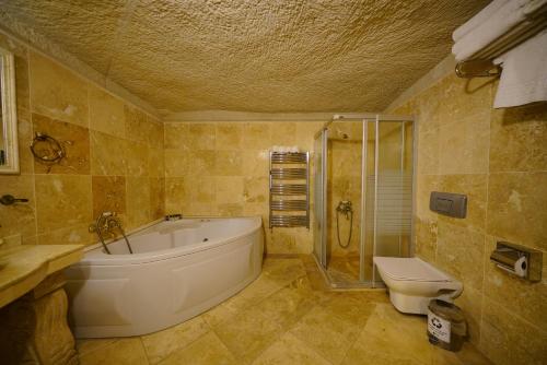 ein Badezimmer mit einer großen Badewanne und einem WC in der Unterkunft Vezir Cave Suites in Goreme