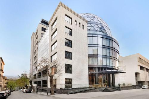 un edificio alto de color blanco con una cúpula de cristal en Wyndham Grand Tbilisi en Tiflis