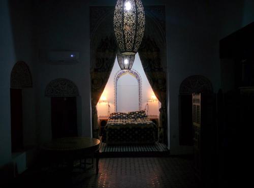Habitación oscura con cama y lámpara de araña. en Riad marco andaloz, en Sale