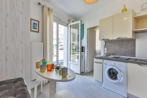 eine Küche mit einem Tisch und einer Waschmaschine in der Unterkunft LE SPOT -T2 à 100m de la grande plage in Saint-Gilles-Croix-de-Vie