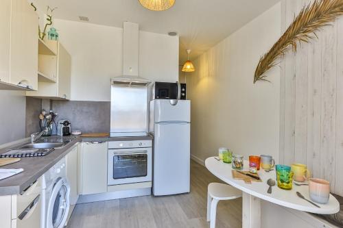 eine Küche mit einem weißen Kühlschrank und einem Tisch in der Unterkunft LE SPOT -T2 à 100m de la grande plage in Saint-Gilles-Croix-de-Vie