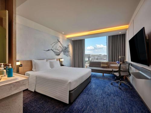 パトゥムターニーにあるノボテルバンコクフューチャーパークランシットのベッド、デスク、テレビが備わるホテルルームです。