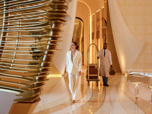 zwei Männer, die in einem Gebäude einen Flur entlang gehen in der Unterkunft Fairmont Doha in Doha