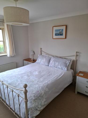 1 dormitorio con 1 cama con colcha blanca en Blakeney Norfolk Bramble Lodge ***Self Catering*** en Blakeney