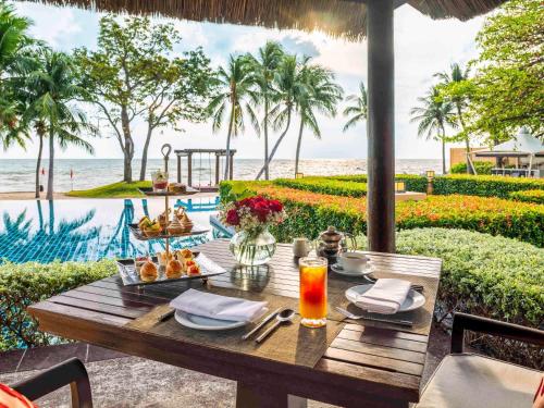 - une table avec de la nourriture et une vue sur l'océan dans l'établissement Mövenpick Asara Resort & Spa Hua Hin, à Hua Hin