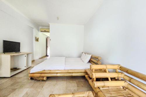 Habitación pequeña con cama y TV. en Kondominium Carita Wawan Mitra RedDoorz, en Pandegelang