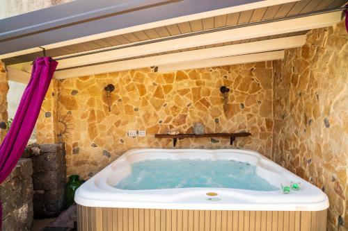 eine Badewanne in einem Zimmer mit einer Steinmauer in der Unterkunft Sikelia Relais 2 in Linguaglossa