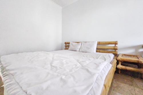 Un dormitorio con una cama con una manta blanca. en Kondominium Carita Wawan Mitra RedDoorz, en Pandegelang