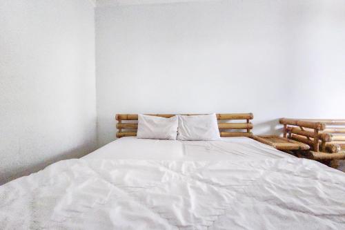 Una cama blanca con dos almohadas encima. en Kondominium Carita Wawan Mitra RedDoorz, en Pandegelang