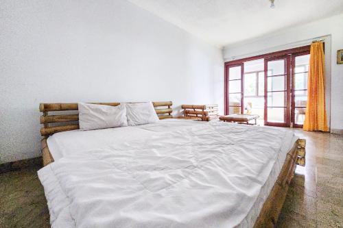 1 cama blanca grande en una habitación con ventana en Kondominium Carita Wawan Mitra RedDoorz, en Pandegelang