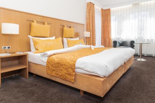 a hotel room with a large bed with yellow pillows at Hotel & Living Am Wartturm - Hotel & Apartments in Speyer