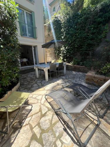 un patio avec des chaises, une table et un parasol dans l'établissement Le Plein Sud, à Bandol