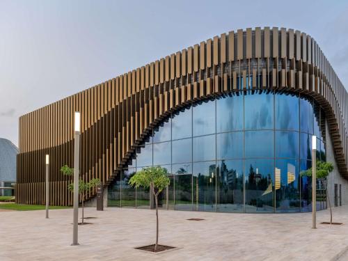 a large glass building with trees in front of it at Sofitel Cotonou Marina Hotel & Spa in Cotonou