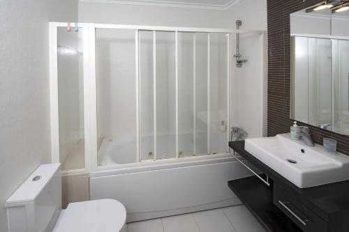 La salle de bains blanche est pourvue d'une douche et d'un lavabo. dans l'établissement Casa Areia Ornata, à Lagos
