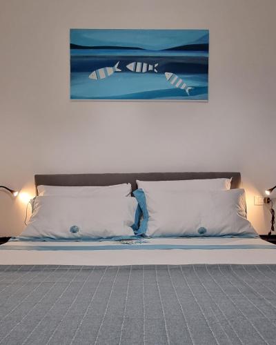 a bed with white pillows and a painting on the wall at Palazzo Sandù Dimora nel Borgo in San Nicola Arcella