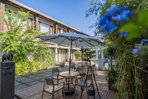 a patio with tables and chairs and an umbrella at Dasein Youlan Hotel-Near the Forbidden City, Tiananmen Square, Guijie Street, Beihai Park, Jingshan Park, and Yonghe Temple in Beijing