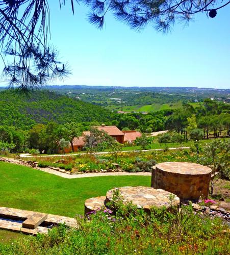 a stone bench sitting on top of a lush green field at Casa dos Sonhos, private terrace, quiet location, walking to village, ecological pool, pets considered, nature friendly in Barão de São João