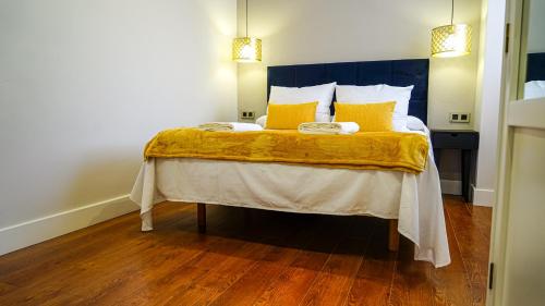 a bedroom with a bed with yellow pillows at Apartamentos Puente Romano Suites Parking Gratis in Merida