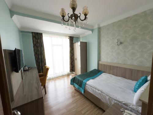 1 dormitorio con 1 cama, TV y lámpara de araña en Kars Center Hotel en Kars