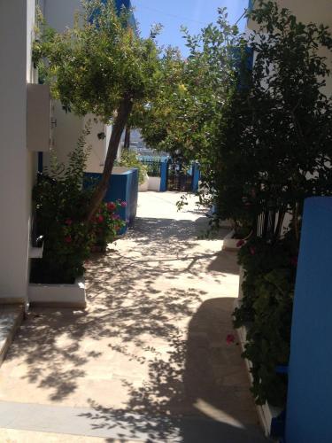 a walkway with trees and flowers on the side of a building at Family sea view apartment near the beach in Makry Gialos