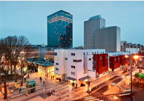 a view of a city at night with tall buildings at Beau studio haut standing de 30m2 in Montreuil