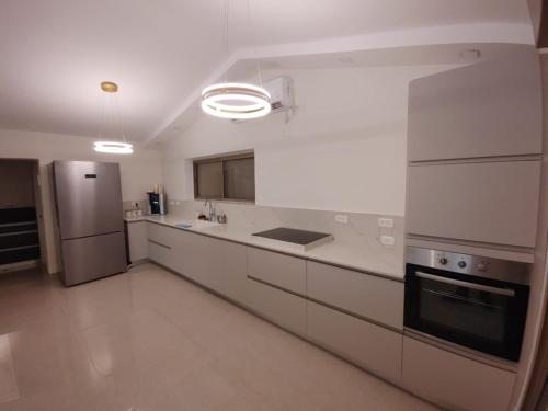 a kitchen with white cabinets and a stainless steel refrigerator at וילה מפוארת על הכינרת in Tiberias