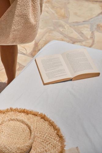 a book on top of a table with a hat at Villa B&M Experience in Sant Francesc de s'Estany