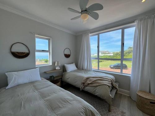 ein Schlafzimmer mit zwei Betten und einem großen Fenster in der Unterkunft High tide at no 16 in St Francis Bay