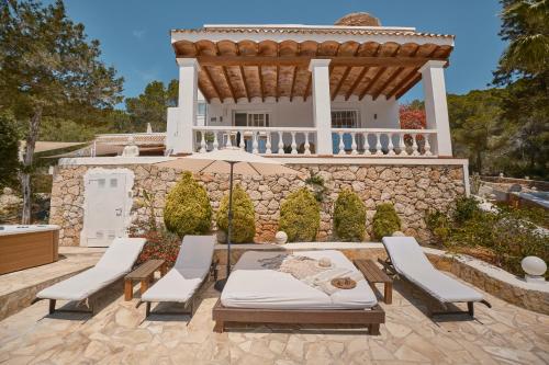 a patio with chairs and an umbrella in front of a house at Villa B&M Experience in Sant Francesc de s'Estany