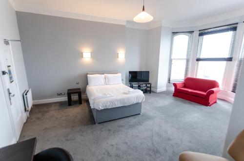 a bedroom with a bed and a red chair at Opul Boutique at Admiral House in Douglas