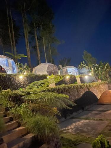 Baturaja的住宿－pinggan sunrise glamping，夜间花园,带帐篷和灯