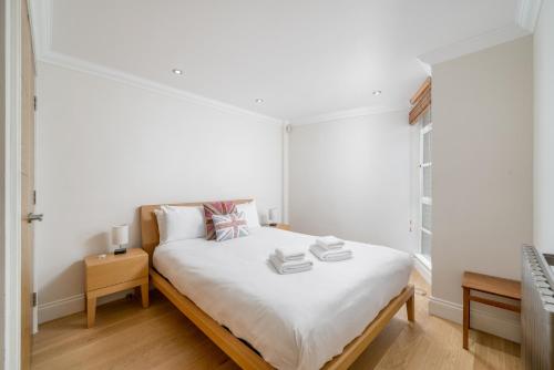 - une chambre dotée d'un lit avec des draps et des livres blancs dans l'établissement Great flat near St Paul’s Cathedral, à Londres