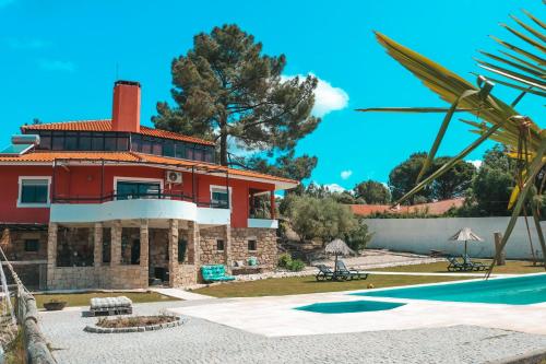 a large red house with a pool in front of it at Charme Lusitano Countryside Experiences in Inguias