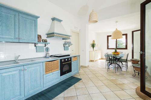 una cucina con armadi blu e tavolo con sedie di La Plage a Fontane Bianche