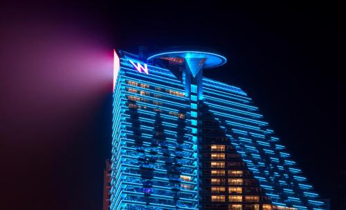 um edifício alto com um sinal fedex sobre ele à noite em W XIAN Hotel em Xi'an