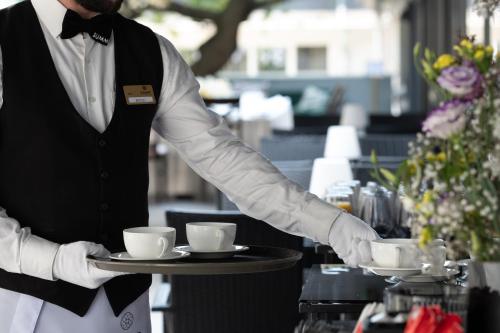 a man holding a tray with cups on it at Summit Villa in Chişinău