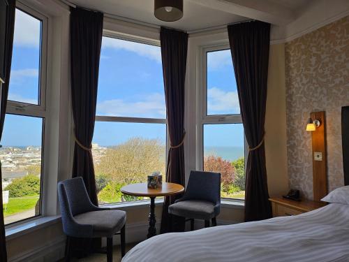 una camera d'albergo con un letto e due sedie e finestre di Geckos Rest a Newquay