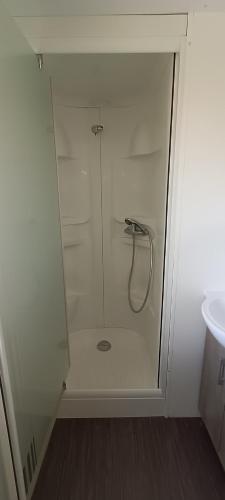 une douche en verre dans une salle de bain avec un lavabo dans l'établissement Mobilhome climatisé 3 chambres à 30 min du Puy du F et de Nantes, à La Boissière-de-Montaigu