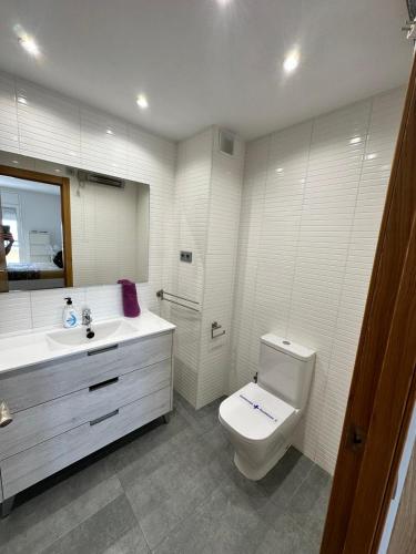 a white bathroom with a toilet and a sink at Apartamento Primera Linea de Mar, Cunit in Cunit
