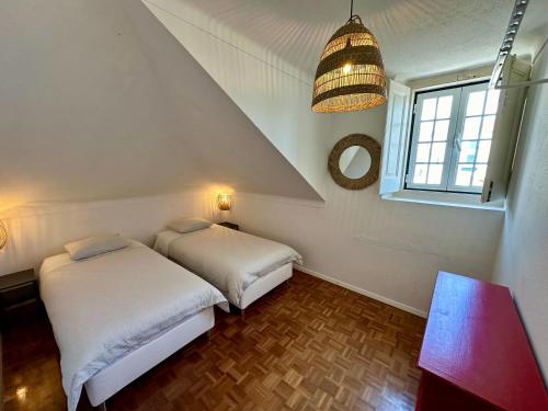 dwa łóżka w małym pokoju z oknem w obiekcie Casa Branca w mieście Ericeira