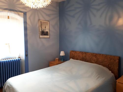 - une chambre avec un lit blanc et un lustre dans l'établissement Maison avec patio centre ville quartier calme, à Arbois