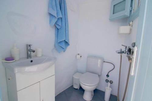 a white bathroom with a toilet and a sink at Lily's Studio in Astypalaia Town