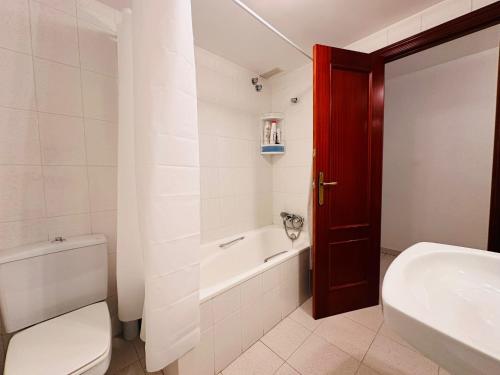 a bathroom with a toilet and a tub and a sink at APARTAMENTO LA GORGA in Boltaña
