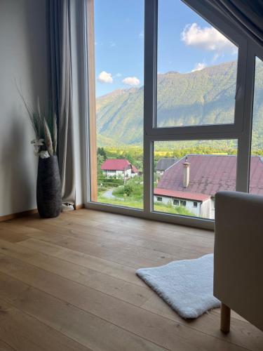 a room with a large window with a view of a house at The Valley Queens in Bovec