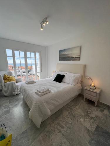 Un dormitorio blanco con una cama grande y una ventana en Nuestro Atico con vistas al Mar Terraza, Piscina y Parking, en Málaga