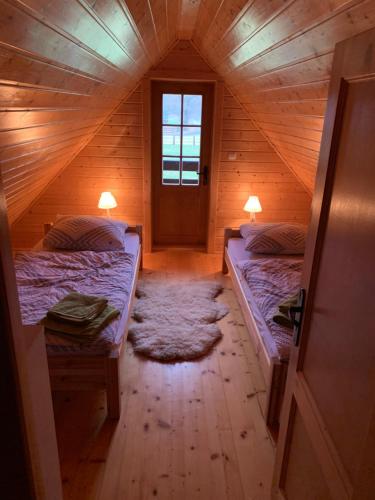 a room with two beds in a wooden house at Leśny Zakątek Uroczysko in Rychtal
