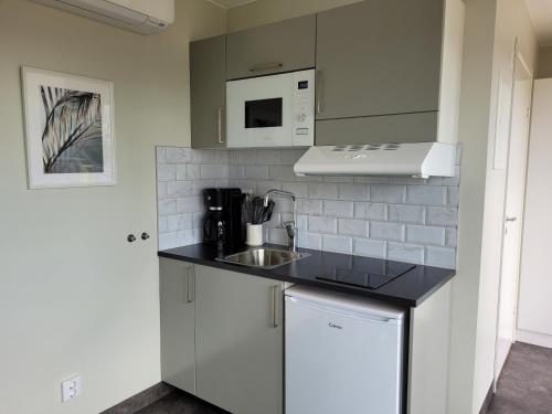 a white kitchen with a sink and a microwave at Halmstad Golfarena stugor in Halmstad