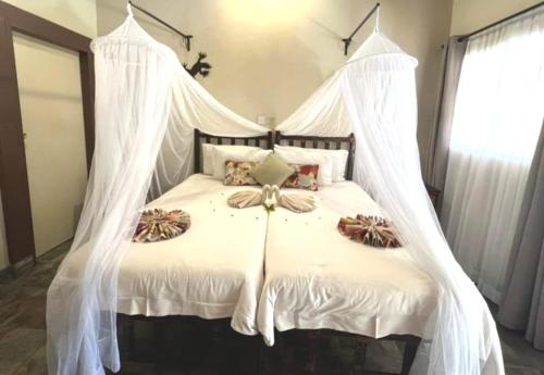 a bedroom with a white bed with mosquito netting at Thebe River Safaris in Kasane
