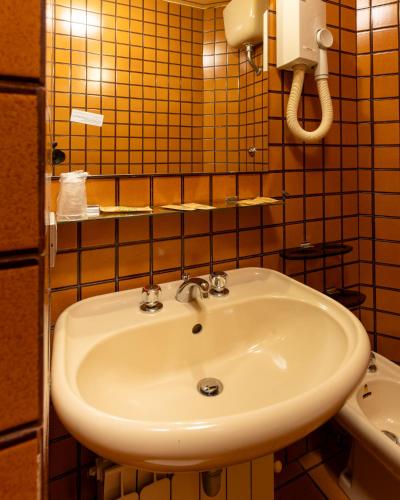 a white sink in a bathroom with yellow tiles at Hotel Terme in Sarnano