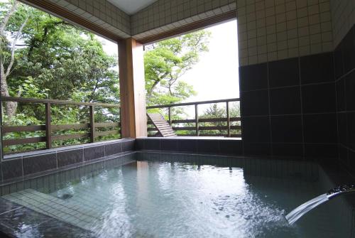 een badkamer met een bad, een raam en water bij Mashio Hotel & Resort in Oshima